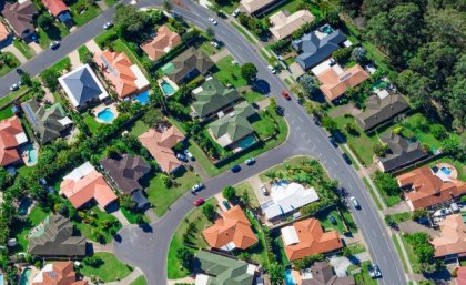 Image: Adobe An aerial photo of a typical Australian suburb, showing roads, house rooftops, backyards and swimming pools.